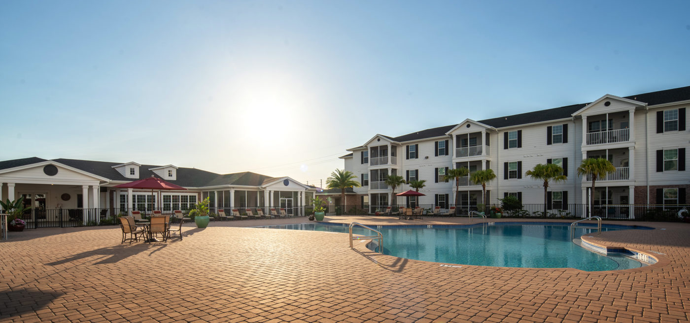 Alternate view of resort-style swimming pool deck with umbrella tables and chairs