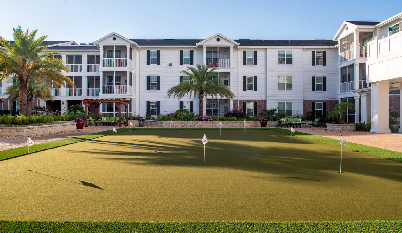 Community put-put course with palm trees near covered trellis seating