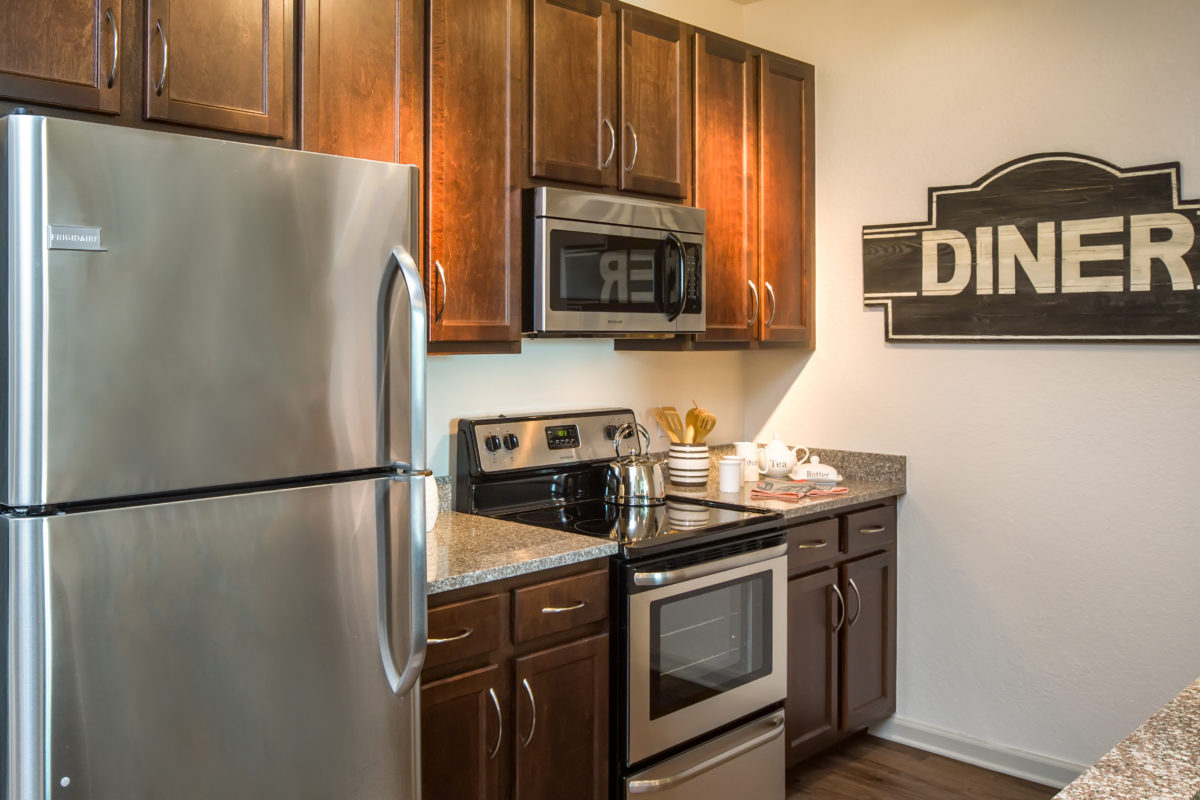 Kitchen with espresso cabinets, stainless steel refrigerator, oven, microwave, and granite countertops