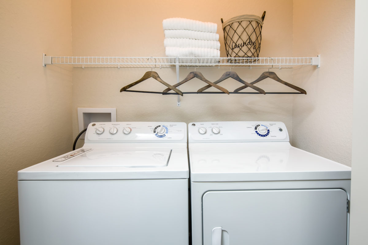 In-unit laundry closet with washer and dryer machine, with rack shelf above