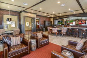 Community pub area with barstools, round tables, and leather armchairs