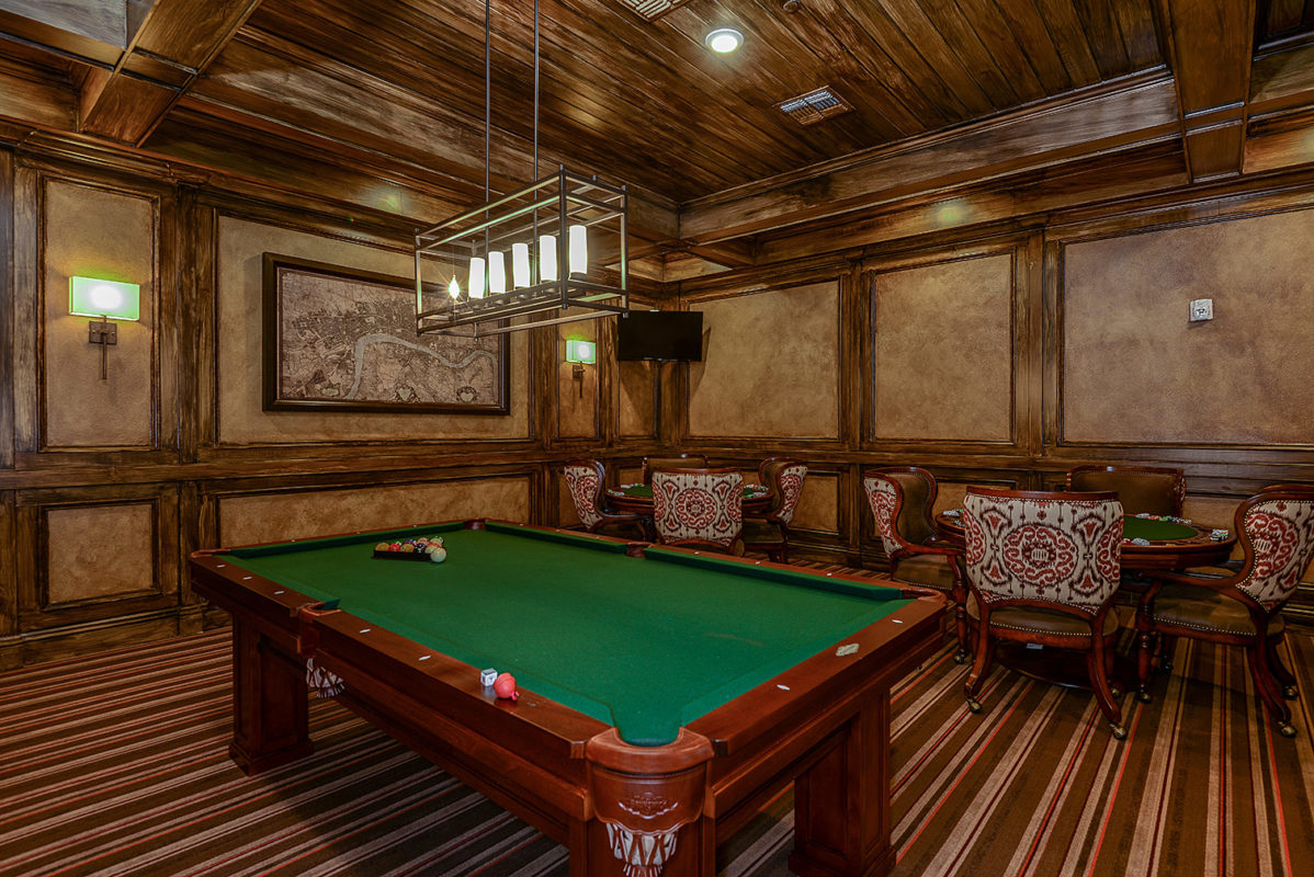 Game room with billiard and pool table next to poker tables
