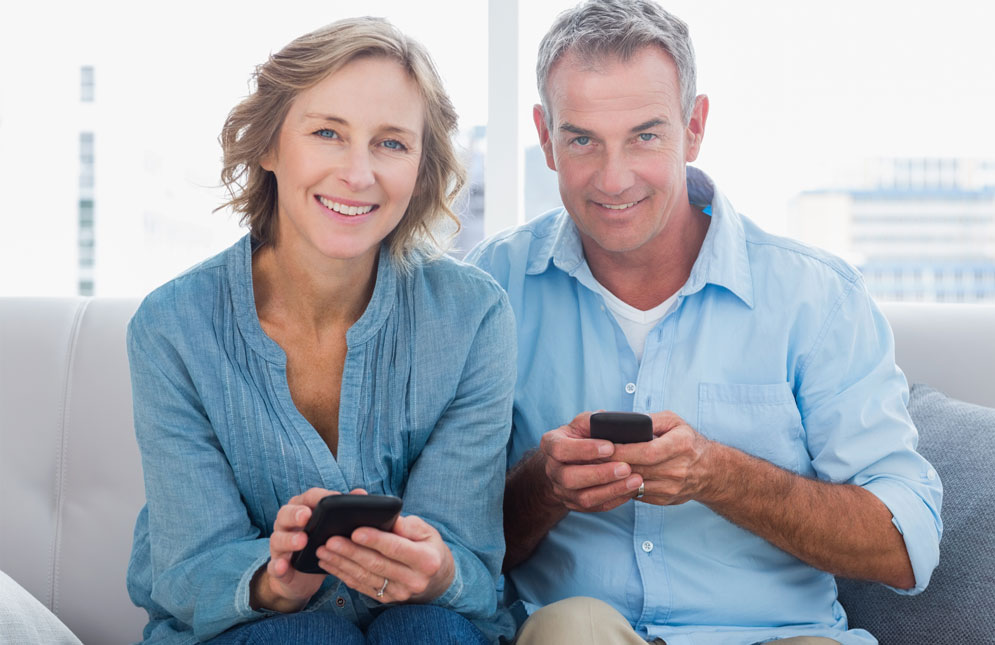 Happy senior couple using smartphones